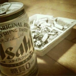 吸い殻でいっぱいの灰皿の隣に置かれたアサヒの缶