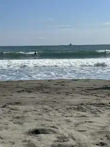 波打ち際と、沖に見える岩。砂に足跡が残る浜