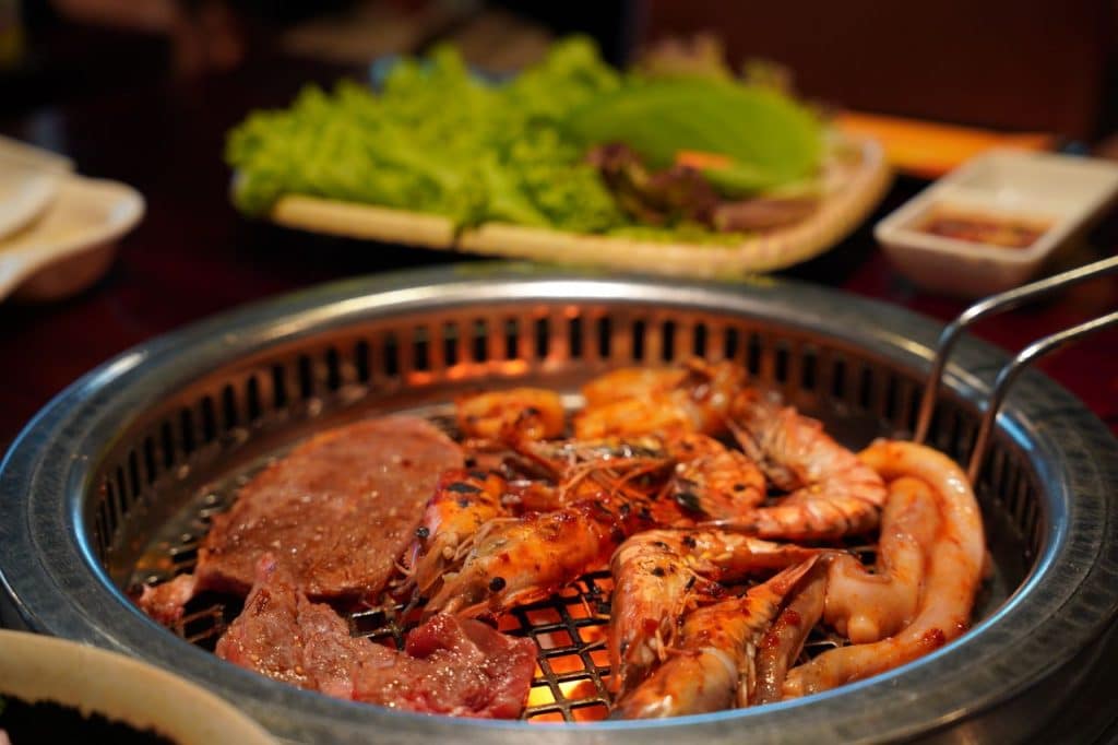 Close-up of grilled shrimp, sausages, and meat on a barbecue grill, perfect for a gourmet meal.
