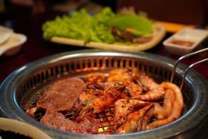 Close-up of grilled shrimp, sausages, and meat on a barbecue grill, perfect for a gourmet meal.